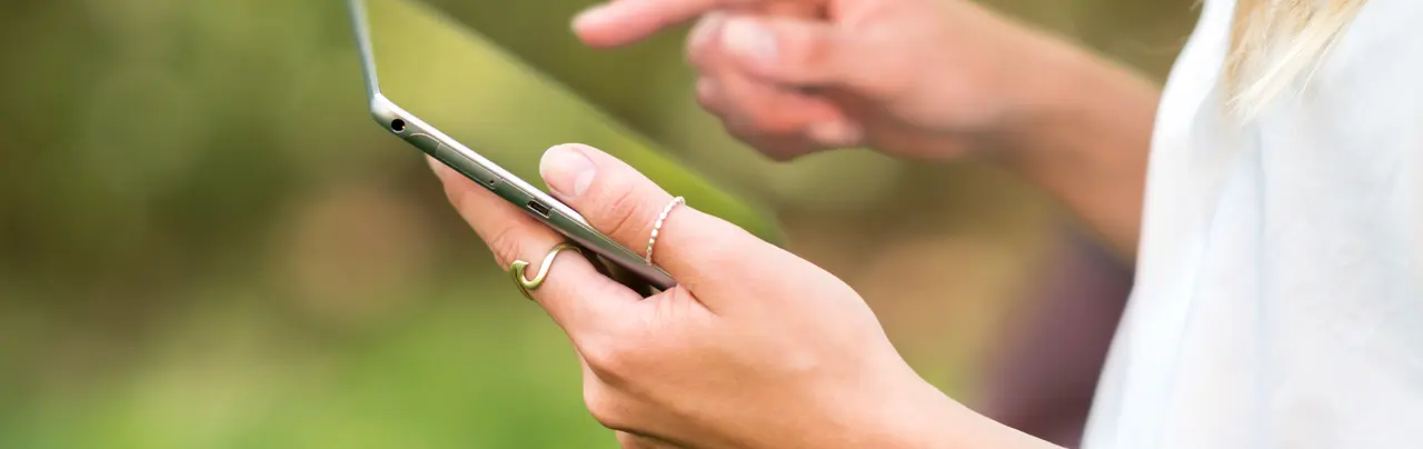 Eine Frau tippt etwas in ihrem Handy ein.